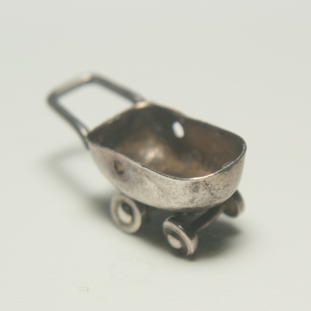 Sterling silver baby carriage 15mm long, 1.10 grams, wheels turn, no hood.